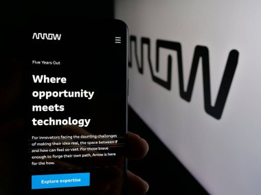 Stuttgart, Almanya - 10-08-2024: ABD 'li Arrow Electronics Inc. şirketinin web sayfası ile akıllı telefon sahibi kişi logonun önünde ekranda. Telefon ekranının merkezine odaklan.