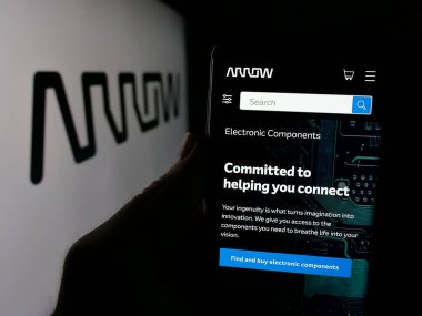 Stuttgart, Almanya - 10-08-2024: ABD 'li Arrow Electronics Inc. şirketinin web sayfası ile cep telefonu sahibi kişi iş logosu önünde ekranda. Telefon ekranının merkezine odaklan.