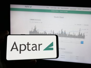 Stuttgart, Almanya - 10-08-2024: Web sayfası önünde ABD 'li ambalaj şirketi AptarGroup Inc. (Aptar) logosu olan cep telefonu sahibi kişi. Telefon ekranına odaklan.