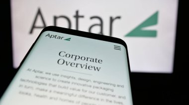 Stuttgart, Germany - 10-08-2024: Smartphone with website of US packaging company AptarGroup Inc. (Aptar) on screen in front of business logo. Focus on top-left of phone display. clipart