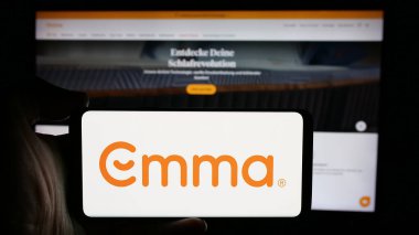 Stuttgart, Almanya - 10-09-2024: Alman şilte şirketi Emma Sleep GmbH 'in logosuyla cep telefonu sahibi kişi iş sayfasının önünde ekranda. Telefon ekranına odaklan.