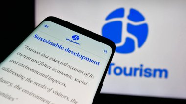 Stuttgart, Almanya - 10-09-2024: Birleşmiş Milletler ajansı BM Turizmi 'nin web sitesinin bulunduğu cep telefonu logonun önünde ekranda. Telefon ekranının sol üst kısmına odaklan.