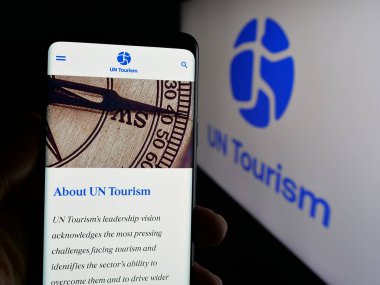 Stuttgart, Almanya - 10-09-2024: Birleşmiş Milletler ajansı BM Turizmi 'nin internet sayfası olan cep telefonu logosu önünde ekranda. Telefon ekranının merkezine odaklan.