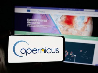 Stuttgart, Almanya - 2024-10-10: ESA Dünya Gözlem Projesi logosu olan cep telefonu sahibi kişi web sayfasının önünde ekranda. Telefon ekranına odaklan.