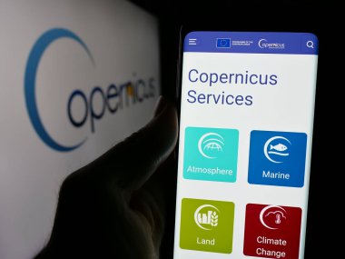 Stuttgart, Almanya - 2024-10-10: ESA Dünya Gözlem Projesi 'nin web sayfası ile cep telefonu tutan kişi logonun önünde ekranda. Telefon ekranının merkezine odaklan.