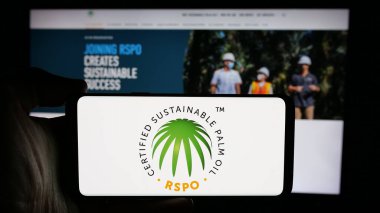 Stuttgart, Almanya - 10-11-2024: Roundtable logosu sürdürülebilir Palm Oil (RSPO) ekranda web sayfasının önünde olan cep telefonu sahibi. Telefon ekranına odaklan.