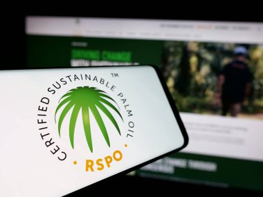 Stuttgart, Germany - 10-11-2024: Mobile phone with logo of Roundtable on Sustainable Palm Oil (RSPO) on screen in front of website. Focus on center-left of phone display. clipart