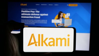 Stuttgart, Almanya - 10-11-2024: ABD 'li finans şirketi Alkami Technology Inc.' in logosuyla cep telefonu sahibi kişi iş sayfasının önünde ekranda. Telefon ekranına odaklan.