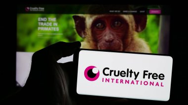 Stuttgart, Germany - 10-11-2024: Person holding mobile phone with logo of organization Cruelty Free International on screen in front of web page. Focus on phone display. clipart