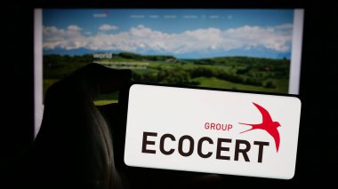 Stuttgart, Almanya - 10-11-2024: İnternet sayfası önünde ekranda organik sertifika organizasyonu ECOCERT logosu bulunan cep telefonu sahibi kişi. Telefon ekranına odaklan.