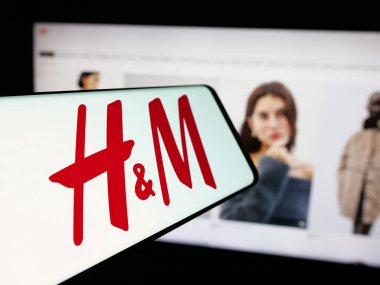 Stuttgart, Almanya - 10-14-2024: İsveçli moda şirketi H ve M (HM) logosu olan akıllı telefon iş dünyasının web sitesinin önünde ekranda. Telefon ekranının merkez soluna odaklan.
