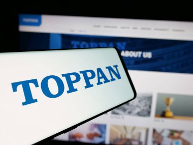 Stuttgart, Almanya - 10-16-2024: Japon şirketi Toppan Holding Inc. 'nin logosunu taşıyan akıllı telefon, iş dünyasının web sitesinin önünde ekranda. Telefon ekranının merkez soluna odaklan.
