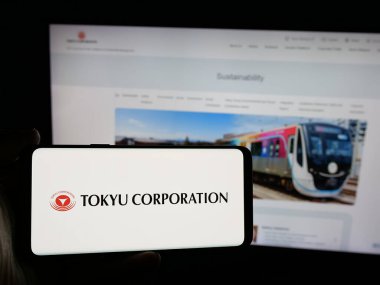 Stuttgart, Almanya - 10-16-2024: Japon holdingi Tokyu Corporation 'ın logosunu elinde tutan kişi web sitesinin önünde ekranda. Telefon ekranına odaklan.