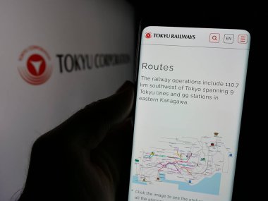 Stuttgart, Almanya - 10-16-2024: Japon holdingi Tokyu Corporation 'ın web sayfası ile ekranda logolu cep telefonu tutan kişi. Telefon ekranının merkezine odaklan.