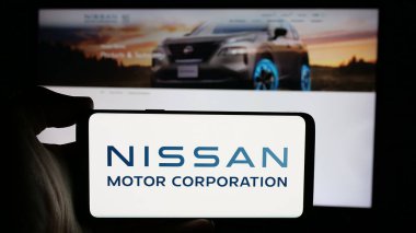 Stuttgart, Almanya - 10-16-2024: Japon Nissan Motor Corporation şirketinin logosuyla cep telefonu sahibi kişi iş sayfasının önünde ekranda. Telefon ekranına odaklan.