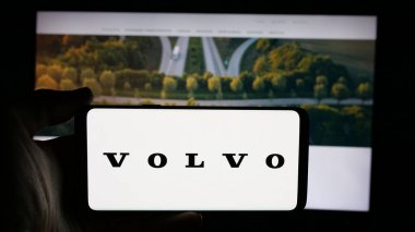 Stuttgart, Almanya - 10-16-2024: İsveçli otomotiv şirketi AB Volvo 'nun logosuyla cep telefonu sahibi kişi iş sayfasının önünde ekranda. Telefon ekranına odaklan.