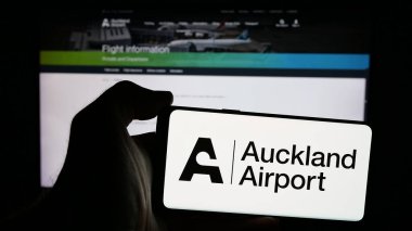 Stuttgart, Almanya - 10-16-2024: Auckland International Airport Limited şirketinin logosuna sahip cep telefonu sahibi kişi web sayfasının önünde ekranda. Telefon ekranına odaklan.