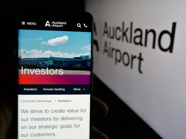 Stuttgart, Almanya - 10-16-2024: Auckland Uluslararası Havalimanı Limited şirketinin web sayfası ile cep telefonu sahibi kişi logo ile ekranda. Telefon ekranının merkezine odaklan.