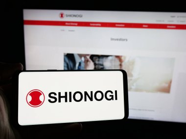 Stuttgart, Almanya - 10-16-2024: Japon ilaç şirketi Shionogi Co. Ltd. nin logosuna sahip kişi web sitesinin önünde ekranda. Telefon ekranına odaklan.