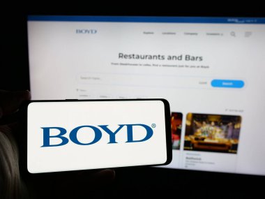 Stuttgart, Almanya - 10-17-2024: ABD 'li konukseverlik şirketi Boyd Gaming Corporation' ın logosunu elinde tutan kişi web sitesinin önünde ekranda. Telefon ekranına odaklan.