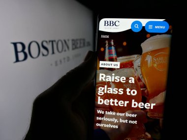 Stuttgart, Almanya - 10-17-2024: ABD bira imalathanesi işletmesi Boston Bira Şirketi 'nin web sayfası logonun önünde cep telefonu tutan kişi. Telefon ekranının merkezine odaklan.