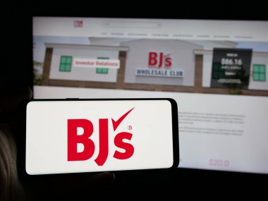 Stuttgart, Almanya - 10-17-2024: Web sayfası önünde ekranda BJ 'in Toptan Kulüp Holding Inc.' sinin logosunun bulunduğu cep telefonu sahibi kişi. Telefon ekranına odaklan.