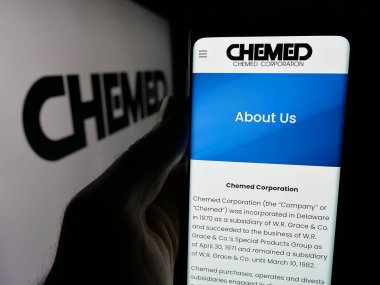 Stuttgart, Almanya - 10-18-2024: ABD holding şirketi Chemed Corporation 'ın web sayfası ile logo önünde cep telefonu tutan kişi. Telefon ekranının merkezine odaklan.