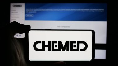 Stuttgart, Germany - 10-18-2024: Person holding cellphone with logo of US holding company Chemed Corporation on screen in front of business webpage. Focus on phone display. clipart