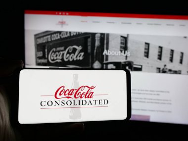 Stuttgart, Almanya - 10-18-2024: Web sitesi önünde ekranda Coca-Cola Consolidated Inc. 'in logosunun bulunduğu akıllı telefon sahibi kişi. Telefon ekranına odaklan.