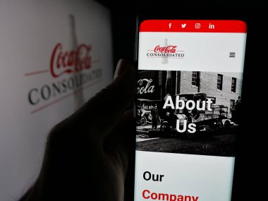 Stuttgart, Almanya - 10-18-2024: ABD 'li Coca-Cola Consolidated Inc.' in web sitesi olan cep telefonu logosu önünde ekranda. Telefon ekranının merkezine odaklan.