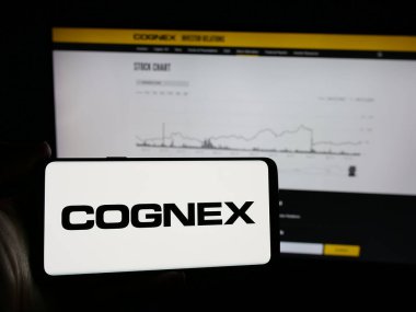 Stuttgart, Almanya - 10-18-2024: Web sayfasının önünde ekranda ABD 'li makine vizyon şirketi Cognex Corporation' ın logosunu taşıyan cep telefonu sahibi kişi. Telefon ekranına odaklan.
