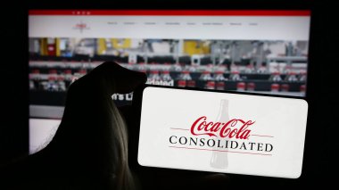 Stuttgart, Almanya - 10-18-2024: Web sayfası önünde ekranda Coca-Cola Consolidated Inc. 'in logosu olan cep telefonu sahibi kişi. Telefon ekranına odaklan.