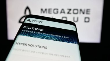 Stuttgart, Germany - 10-18-2024: Mobile phone with website of South Korean company MegazoneCloud Corp. on screen in front of business logo. Focus on top-left of phone display. clipart