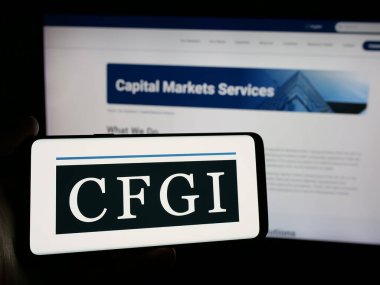 Stuttgart, Almanya - 10-18-2024: Amerikan danışmanlık şirketi CFGI 'nin logosuyla cep telefonu sahibi kişi iş sayfasının önünde ekranda. Telefon ekranına odaklan.