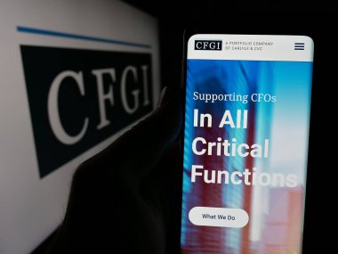 Stuttgart, Almanya - 10-18-2024: ABD 'li danışmanlık şirketi CFGI' nin web sitesi ile cep telefonu sahibi kişi iş logosu önünde ekranda. Telefon ekranının sol üst kısmına odaklan.