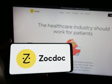 Stuttgart, Almanya - 10-21-2024: ABD 'li teletıp şirketi Zocdoc Inc.' in logosunu elinde tutan kişi web sitesinin önünde ekranda. Telefon ekranına odaklan.