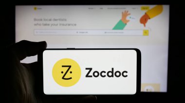 Stuttgart, Almanya - 10-21-2024: ABD 'li teletıp şirketi Zocdoc Inc.' in logosuyla cep telefonu sahibi kişi iş sayfasının önünde ekranda. Telefon ekranına odaklan.