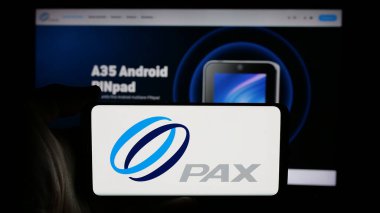 Stuttgart, Almanya - 10-22-2024: Çinli ödeme şirketi PAX Technology 'nin logosuyla cep telefonu sahibi kişi iş sayfasının önünde ekranda. Telefon ekranına odaklan.