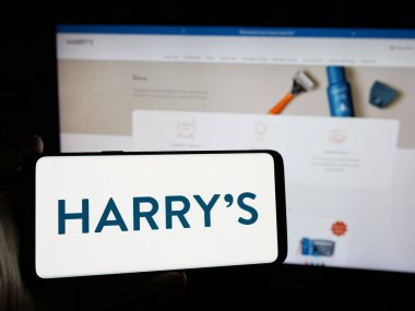 Stuttgart, Almanya - 10-22-2024: ABD 'li traş ekipmanları şirketi Harry' s Inc. 'in logosuna sahip akıllı telefon sahibi kişi web sitesinin önünde ekranda. Telefon ekranına odaklan.
