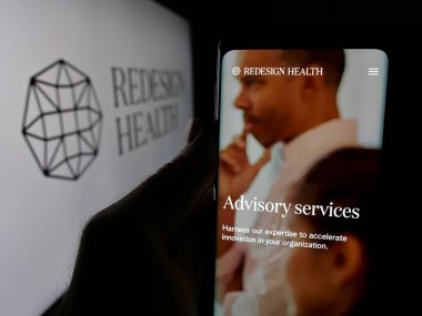 Stuttgart, Almanya - 10-23-2024: ABD 'li sağlık şirketi Redesign Health Inc.' in web sitesi ile cep telefonu tutan kişi logolu ekranda. Telefon ekranının merkezine odaklan.