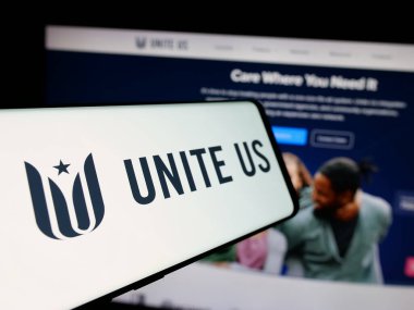 Stuttgart, Almanya - 10-23-2024: Sosyal hizmet şirketi Unite USA Inc. 'in logosuna sahip cep telefonu. (ABD' yi Birleştir) İnternet sitesi önünde ekranda. Telefon ekranının merkez soluna odaklan.