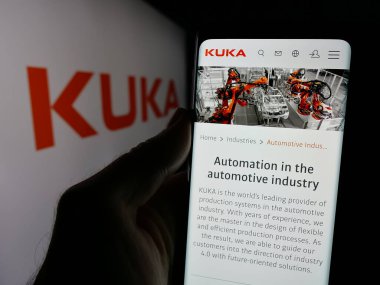 Stuttgart, Almanya - 10-24-2024: Alman endüstriyel otomasyon şirketi Kuka AG 'nin internet sayfası ile cep telefonu tutan kişi logolu ekranda. Telefon ekranının merkezine odaklan.