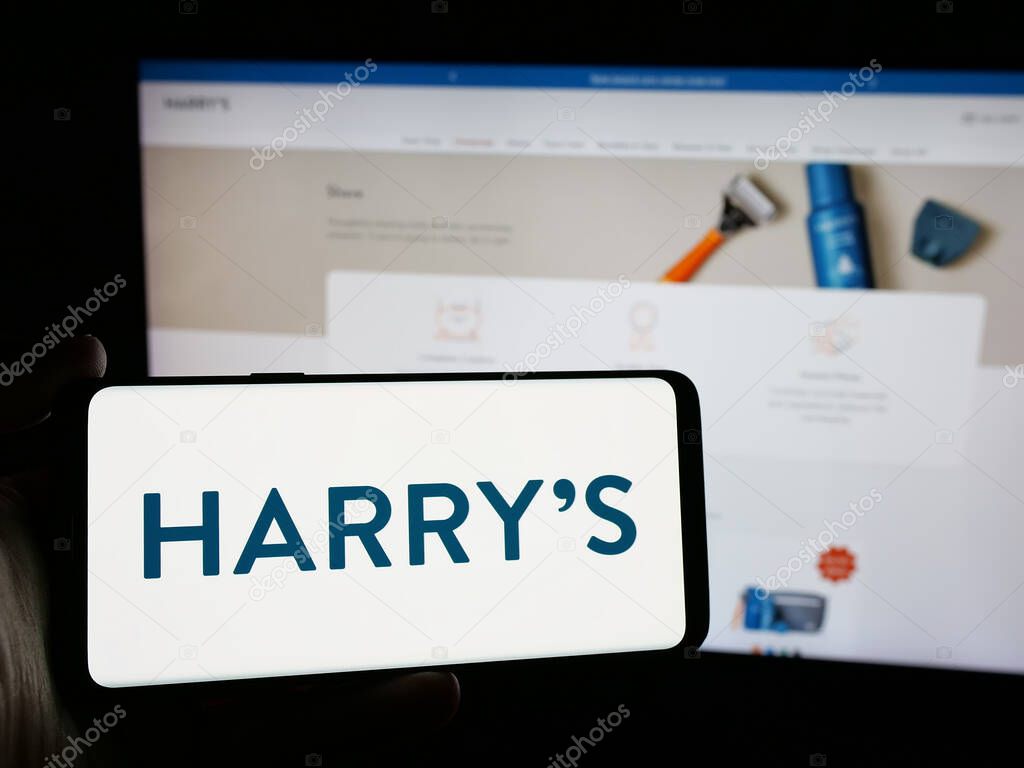 Stuttgart, Germany - 10-22-2024: Person holding smartphone with logo of US shaving equipment company Harry's Inc. on screen in front of website. Focus on phone display.