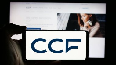 Stuttgart, Almanya - 10-24-2024: İnternet sayfası önünde üzerinde Credit Commercial de France (CCF) logosu bulunan cep telefonu sahibi kişi. Telefon ekranına odaklan.