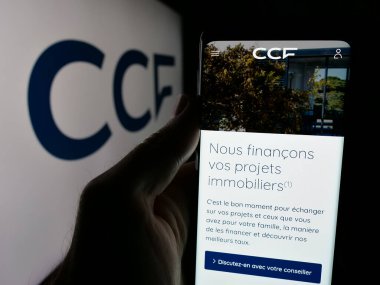 Stuttgart, Almanya - 10-24-2024: Logo önündeki ekranda Credit Commercial de France (CCF) şirketinin web sayfası bulunan kişi. Telefon ekranının merkezine odaklan.