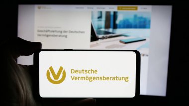Stuttgart, Almanya - 10-25-2024: Web sayfası önünde Deutsche Vermogensberatung AG (DVAG) şirketinin logosunun bulunduğu cep telefonu sahibi kişi. Telefon ekranına odaklan.