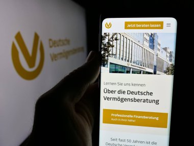 Stuttgart, Almanya - 10-25-2024: Deutsche Vermoegensberatung AG (DVAG) şirketinin web sayfasını elinde tutan kişi logo ile ekranda. Telefon ekranının merkezine odaklan.