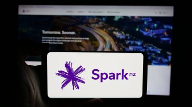 Stuttgart, Almanya - 10-25-2024: Telekom şirketi Spark New Zealand Limited 'in logosunun bulunduğu cep telefonu sahibi kişi iş sayfasının önünde ekranda. Telefon ekranına odaklan.