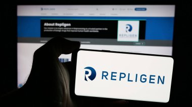 Stuttgart, Almanya - 10-25-2024: ABD 'li ilaç şirketi Repligen Corporation' ın logosunu elinde tutan kişi web sitesinin önünde ekranda. Telefon ekranına odaklan.