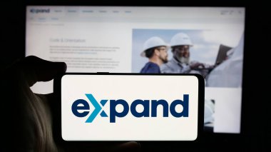 Stuttgart, Almanya - 10-25-2024: ABD 'li şirket Expand Energy Corporation' ın logosunu elinde tutan kişi web sitesinin önünde ekranda. Telefon ekranına odaklan.